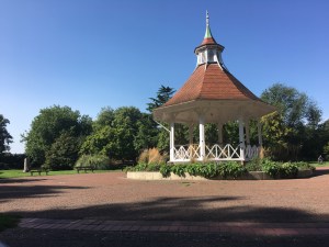 A large open space, park area with a bandstand in the middle. There are clear blue skies in the photo.