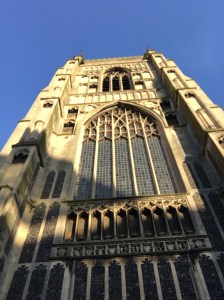 Looking up at the outside architecture of a church. You can see it is made from stone and has intricate ironwork windows.