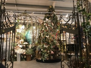 Ironwork gates leading to a magnificent Christmas tree in the garden centre. There are lights and gold decorations 