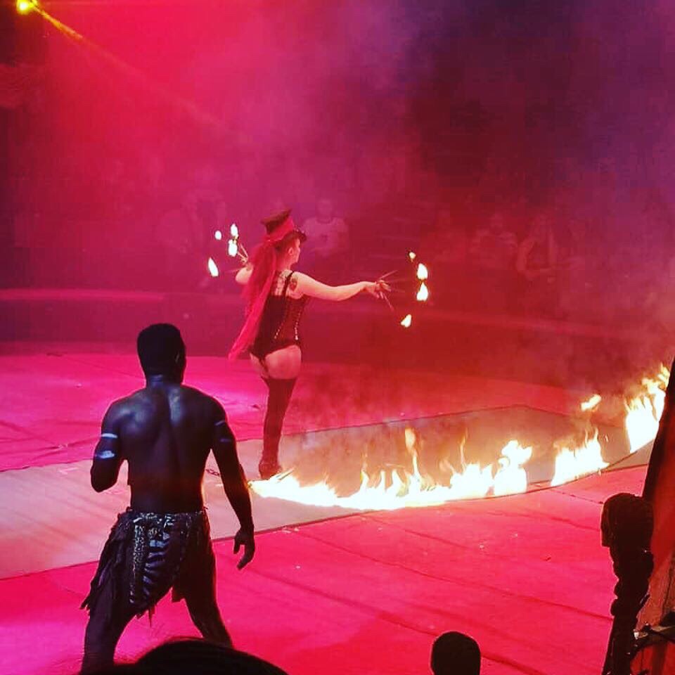 A lady in a black top hat is skipping with a rope that is on fire. She also has flames coming from her fingers. 