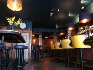 Photo taken at wheelchair sitting height, the bar is on the right with high stools and opposite are more high tables with stools. Too high for a wheelchair user