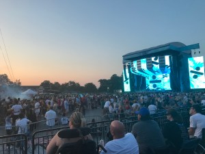 The sun is setting, the sky turns pink and the stage is lit up blue, as we wait for Ed Sheeran