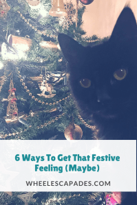An image to pin. Title text 6 Ways To Get That Festive Feeling is placed over the photo of fluffy cat photobombing the Christmas tree. 