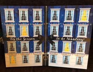 Is the season to be nibbling. Is written on the inside of the calendar. The layout is of windows of a house, each one opening up to reveal the days cheese.