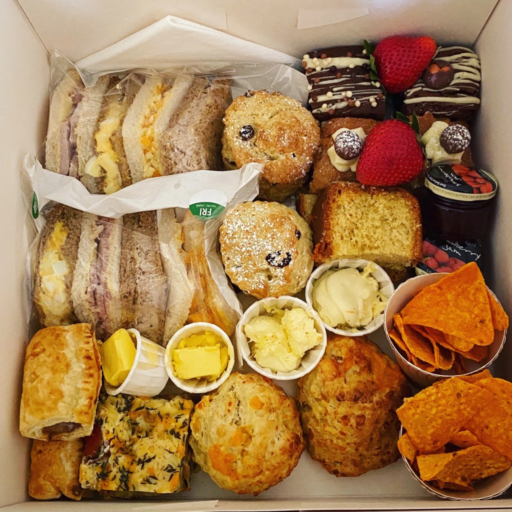 A white cardboard cake box filled with all the afternoon tea treats listed below in the post.