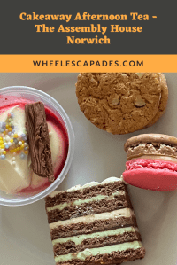 An image to pin. Title text in orange on dark grey at the top quarter reads Cakeaway Afternoon Tea - The Assembly House Norwich. The other three quarters of the image is a close up of the four desserts. Gateau, macaron, cookie and potted dessert. 