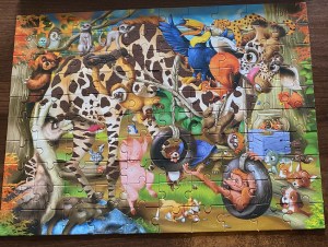 Completed jigsaw puzzle of cartoon character animals including a giraffe, pig, monkeys and birds. The puzzle has 100 pieces.